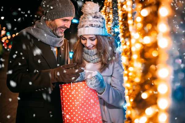 Пара с рождественским подарком после прогулок по украшенной улице — стоковое фото