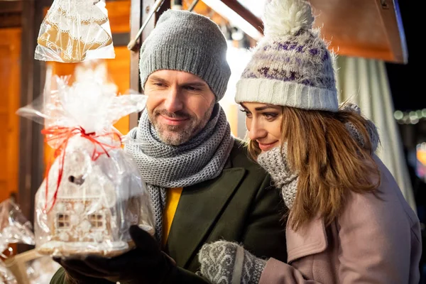 Um belo casal passa o tempo juntos no mercado de Natal olhando para os produtos nas barracas — Fotografia de Stock
