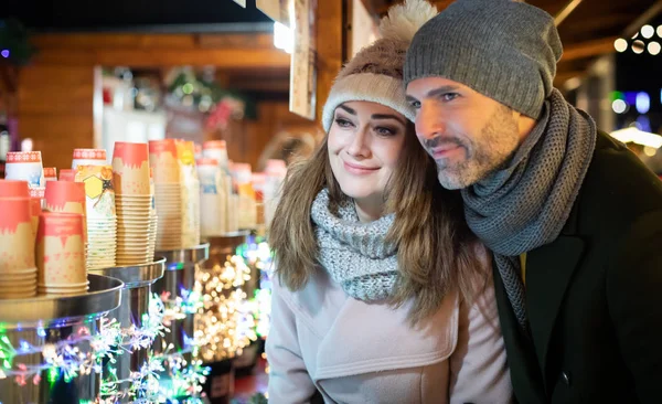 Pěkný pár tráví čas spolu na vánočním trhu při pohledu na výrobky ve stáncích — Stock fotografie