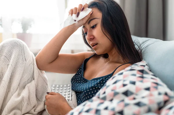 Asian girl suffering from cold sitting on bed at home — Stock Photo, Image