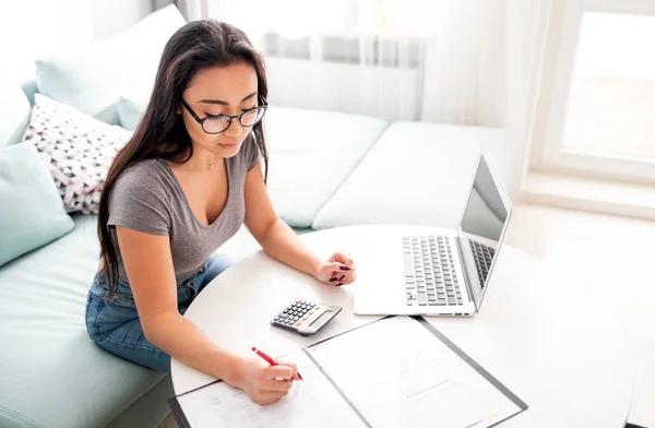Азійська жінка використовує калькулятор і ноутбук для пом'якшення податків на домашні бюджети. — стокове фото