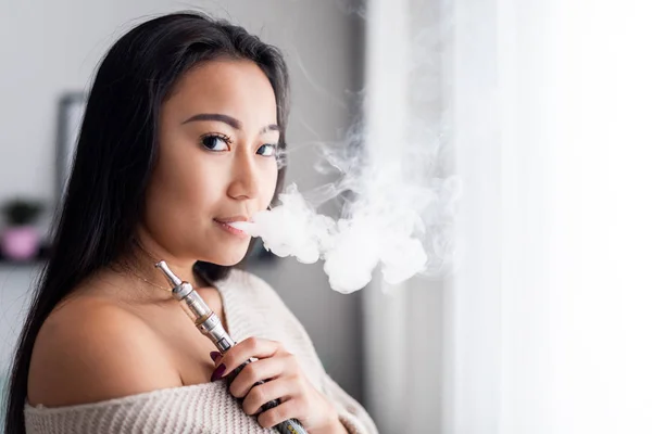 Casual mulher asiática vaping cigarro eletrônico em casa — Fotografia de Stock