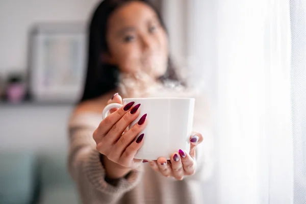 Cup of tea or coffee in hand of asian woman at home — Stock Photo, Image