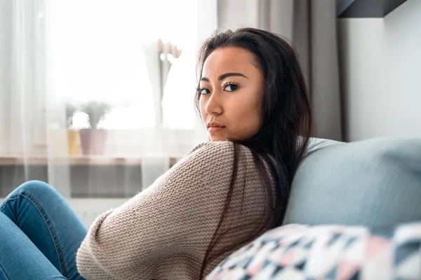 Gadis asia tertekan duduk di sofa di rumah dan berpikir — Stok Foto