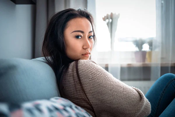 Deprimido asiático chica sentado en sofá en casa y pensando — Foto de Stock