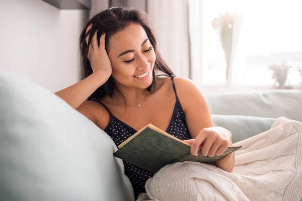 Konzentrierte asiatische Mädchen liegen auf dem Sofa und lesen ein Buch zu Hause — Stockfoto