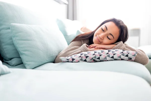 Glücklich asiatisch mädchen liegend auf sofa mit kissen bei zuhause — Stockfoto