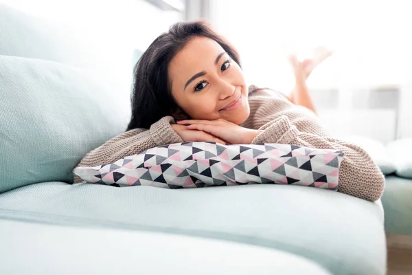 Szczęśliwy Azji dziewczyna leżące na kanapie z poduszką w domu — Zdjęcie stockowe