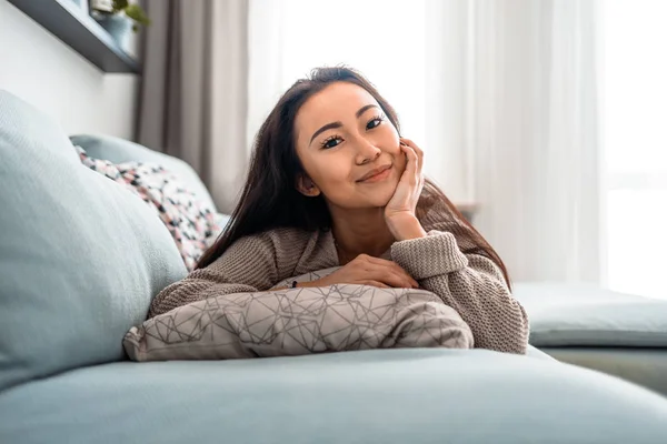 Entspanntes asiatisches Mädchen liegt in ruhiger Freizeit zu Hause auf dem Sofa — Stockfoto