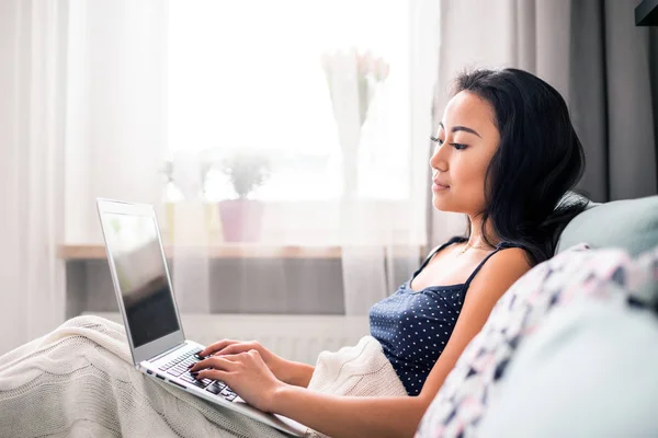 Relajado asiático chica usando laptop sentado en sofá en casa —  Fotos de Stock