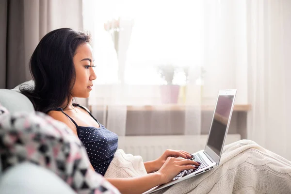 Relajado asiático chica usando laptop sentado en sofá en casa —  Fotos de Stock