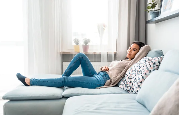 Entspannt lächelnd asiatische Frau sitzt auf Sofa zu Hause — Stockfoto