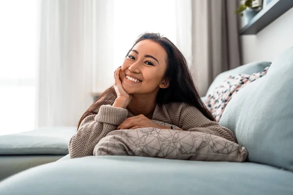 Relajado sonriente asiático mujer sentado en sofá en casa — Foto de Stock