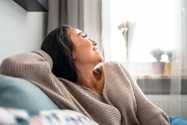 Розслаблена усміхнена азіатська жінка сидить на дивані вдома — стокове фото