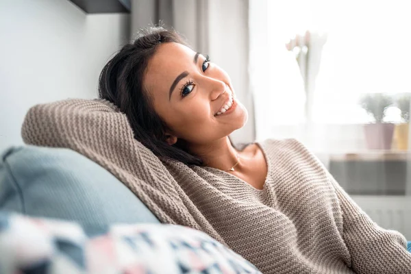 Розслаблена усміхнена азіатська жінка сидить на дивані вдома — стокове фото