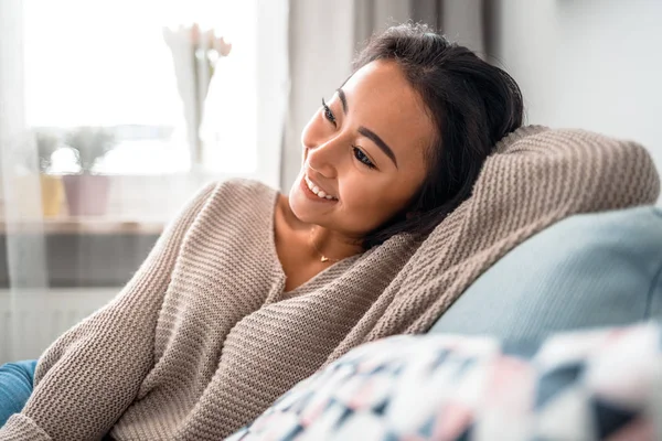 Relaks uśmiechnięta azjatka kobieta siedzi na kanapie w domu — Zdjęcie stockowe