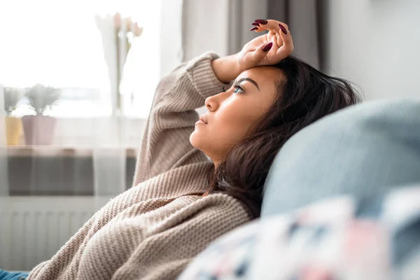 Sad asian girl sitting on sofa at home and thinking — Stock Photo, Image