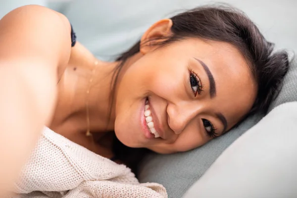 Glimlachende aziatische jonge vrouw liggend in bed thuis — Stockfoto