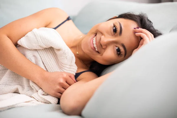 Улыбающаяся азиатская молодая женщина, лежащая в постели дома — стоковое фото
