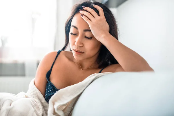 Upset depressed asian girl on couch suffering from headache migraine — Stock Photo, Image