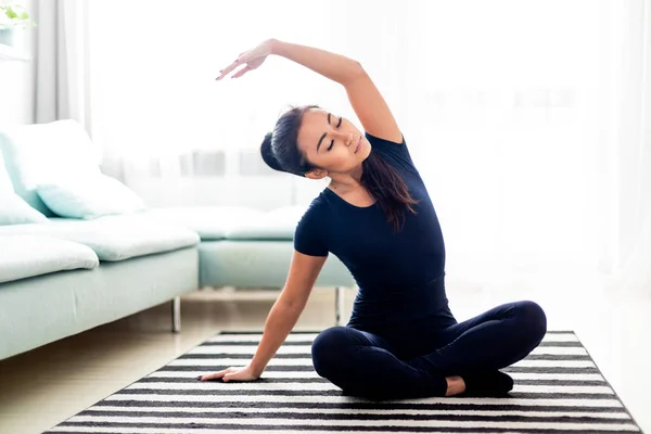 Jeune fille asiatique exerçant à la maison sur le tapis dans le salon — Photo