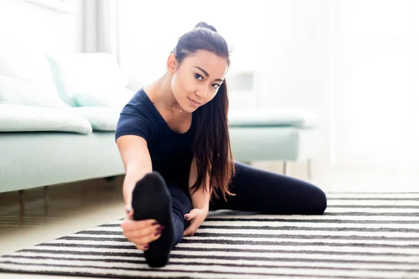 Ung asiatisk pige træning hjemme på tæppe i stuen - Stock-foto
