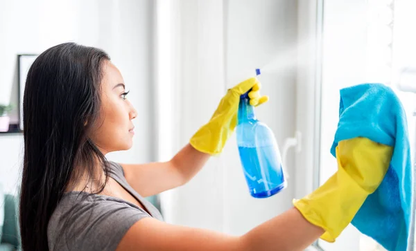 Joven asiática chica con guantes y spray limpieza ventanas — Foto de Stock