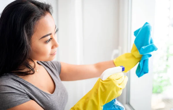 Joven asiática chica con guantes y spray limpieza ventanas — Foto de Stock