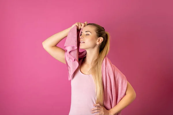 若いですフィット女性疲れ後ワークアウトとともにタオルで彼女の肩上のピンクの背景 — ストック写真