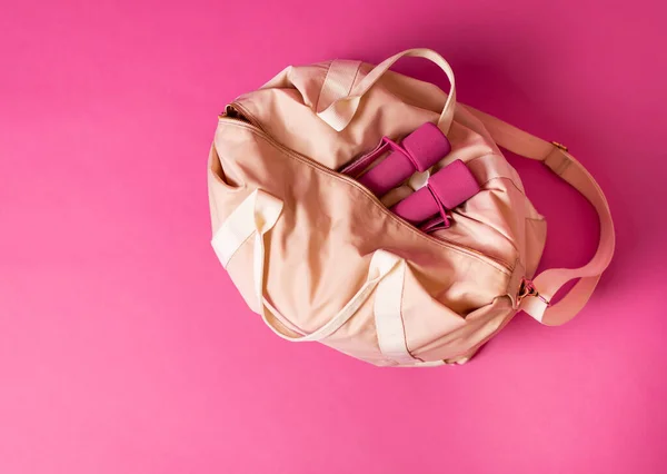 女性スポーツバッグとともにダンベル嘘ピンクの背景 — ストック写真