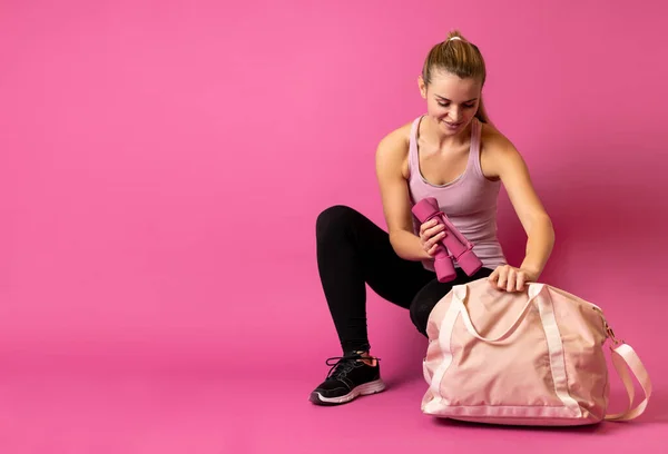 Fit Frau Packt Die Hanteln Die Sporttasche Auf Rosa Hintergrund — Stockfoto