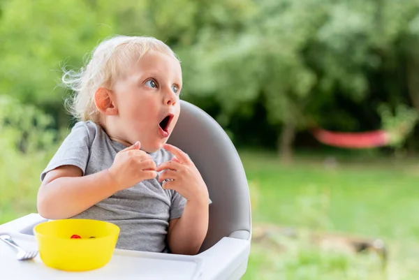 屋外で食事をしながら何かを見て驚きの赤ちゃん — ストック写真