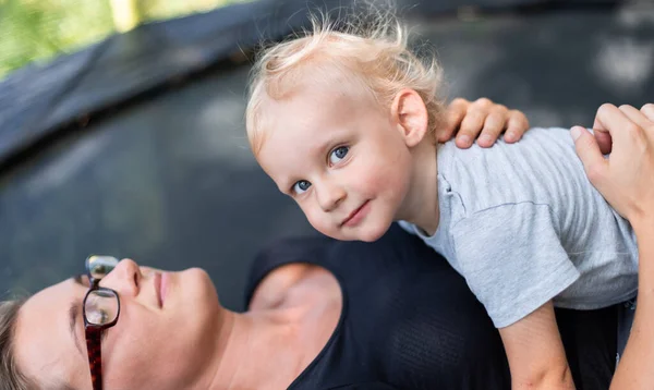 Kleines Kind Liegt Mit Seiner Mutter Auf Trampolin Garten — Stockfoto