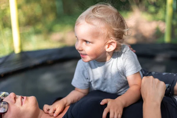Klein Kind Met Zijn Moeder Liggen Trampoline Outdoor Achtertuin — Stockfoto