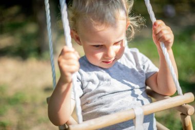 Arka bahçede bebek salıncağında oturan mutlu küçük çocuk.