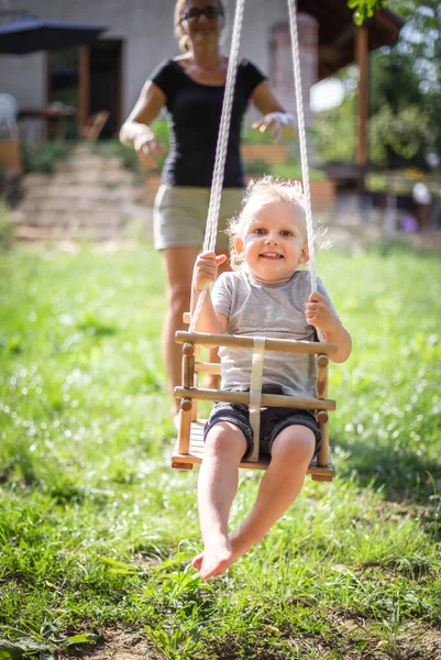 Gelukkig Moeder Duwen Lachen Zoon Swing Achtertuin — Stockfoto