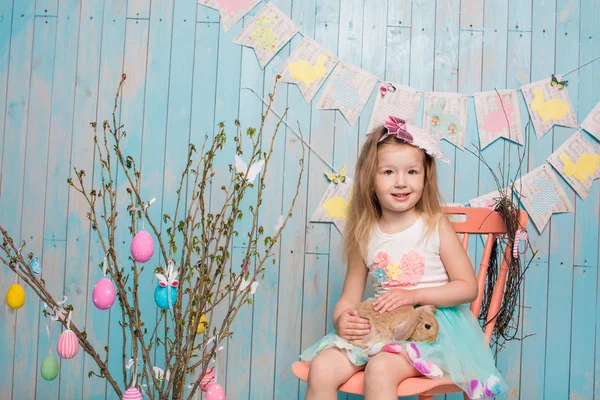 Pequeña hermana hermosa y encantadora chica junto con el conejo sentado en el suelo o silla en ropa azul brillante Pascua, huevos, humor festivo, emoción y sonrisa fiesta sorpresa celebración —  Fotos de Stock