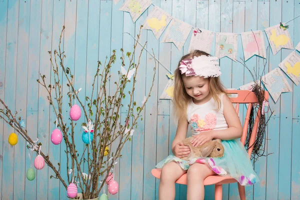 Pequeña hermana hermosa y encantadora chica junto con el conejo sentado en el suelo o silla en ropa azul brillante Pascua, huevos, humor festivo, emoción y sonrisa fiesta sorpresa celebración —  Fotos de Stock