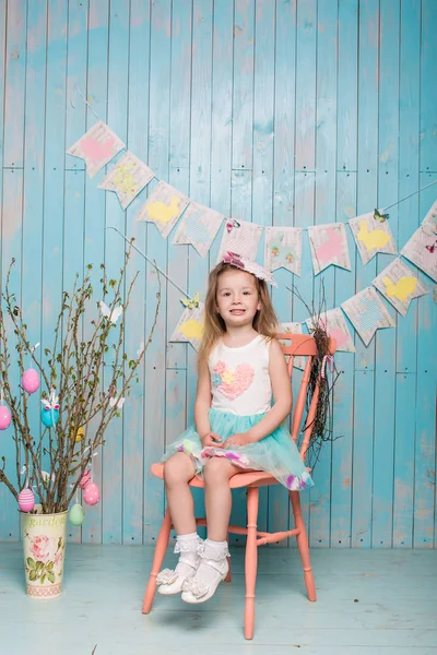 Little beautiful and charming girl sister along with rabbit sitting on the floor or chair in bright blue clothes Easter, eggs, festive mood, emotion and smile surprise holiday celebration — Stock Photo, Image