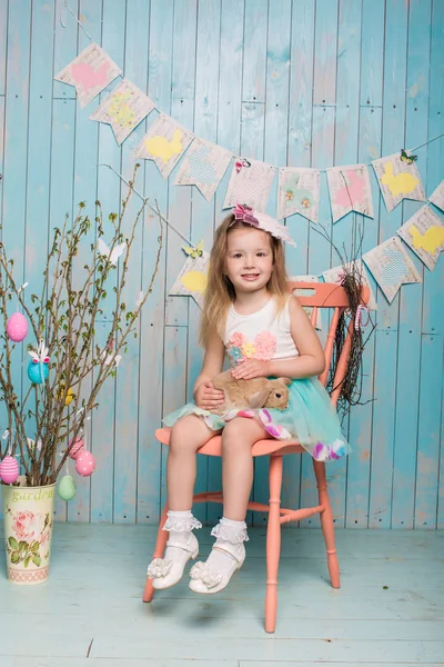 Pequeña hermana hermosa y encantadora chica junto con el conejo sentado en el suelo o silla en ropa azul brillante Pascua, huevos, humor festivo, emoción y sonrisa fiesta sorpresa celebración —  Fotos de Stock