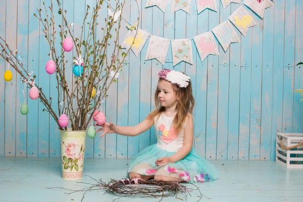 Little beautiful and charming girl sister along with rabbit sitting on the floor or chair in bright blue clothes Easter, eggs, festive mood, emotion and smile surprise holiday celebration — Stock Photo, Image