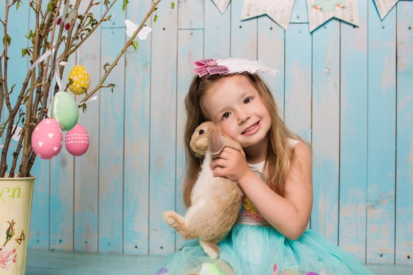 Pequeña hermana hermosa y encantadora chica junto con el conejo sentado en el suelo o silla en ropa azul brillante Pascua, huevos, humor festivo, emoción y sonrisa fiesta sorpresa celebración —  Fotos de Stock