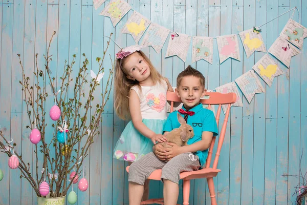 İki küçük childs, oğlum, kız kardeşi ve kız kardeşi ile birlikte parlak yerde oturan tavşan mavi elbise Paskalya, yumurta, şenlikli ruh, duygu ve gülümseme sürpriz tatil kutlaması