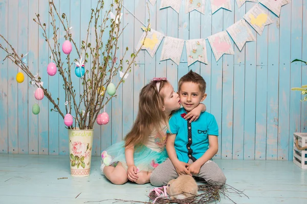 Dos niños pequeños, niño, niña, hermano y hermana junto con el conejo sentado en el suelo en ropa azul brillante Pascua, huevos, humor festivo, emoción y sonrisa fiesta sorpresa celebración —  Fotos de Stock