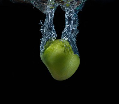 Siyah arka plan üzerine düşen suya yeşil elma