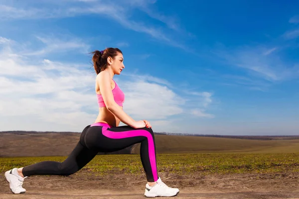 Молодая женщина делает упражнения на голубом фоне неба — стоковое фото