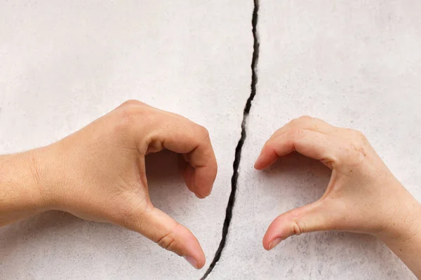 Hands in the shape of heart on cracked wall — Stock Photo, Image