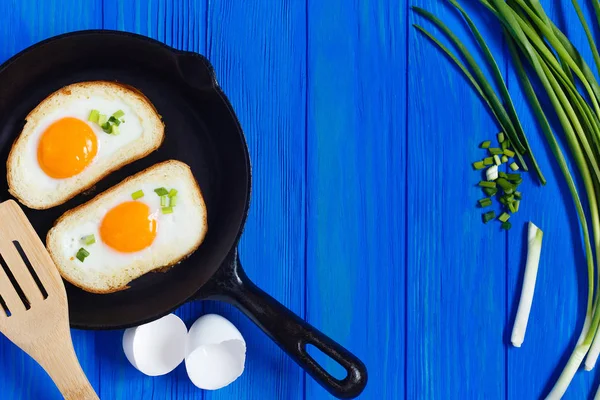 Смажені яйця, хрусткий тост і весняна цибуля на синьому дерев'яному столі — стокове фото