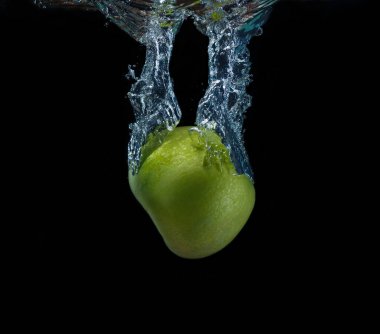 Siyah arka plan üzerine düşen suya yeşil elma