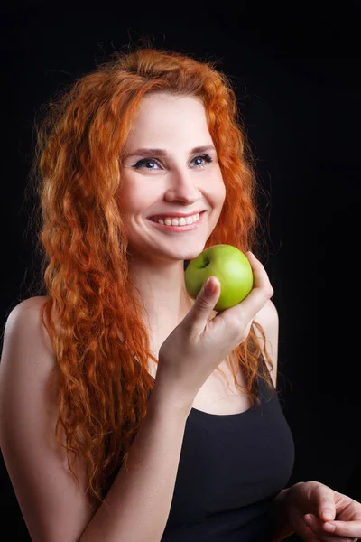 Piękna młoda redhead kobieta uśmiechając się trzyma jabłko — Zdjęcie stockowe